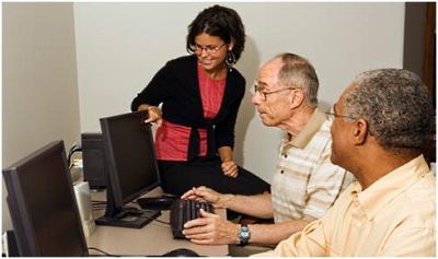 A group of people around a computer screen
